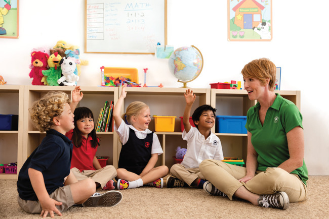 children smiling and sitting around teacher