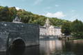 Un château du Périgord vu depuis la rivière, devant une forêt