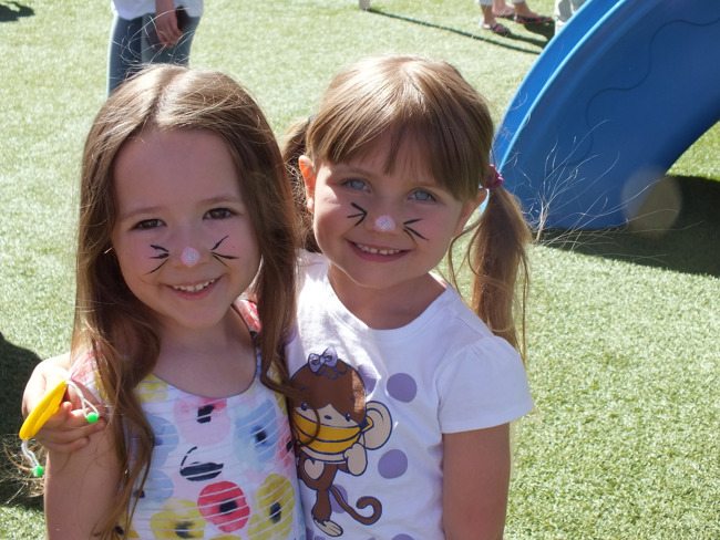 Two little girls with whiskers painted on their faces celebrating spring fling
