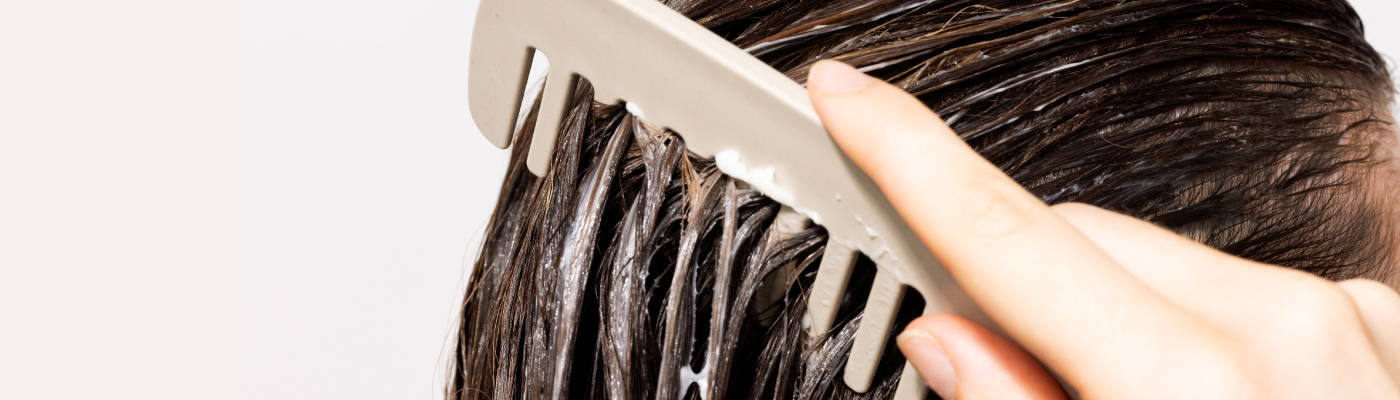 close up of a comb being brushed through wet, brunette hair