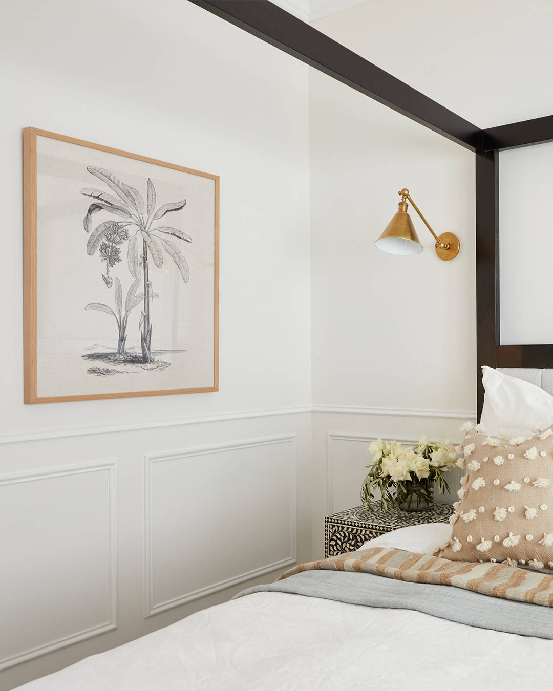 A framed artwork featuring a palm illustration hangs on the wall of this bedroom setting