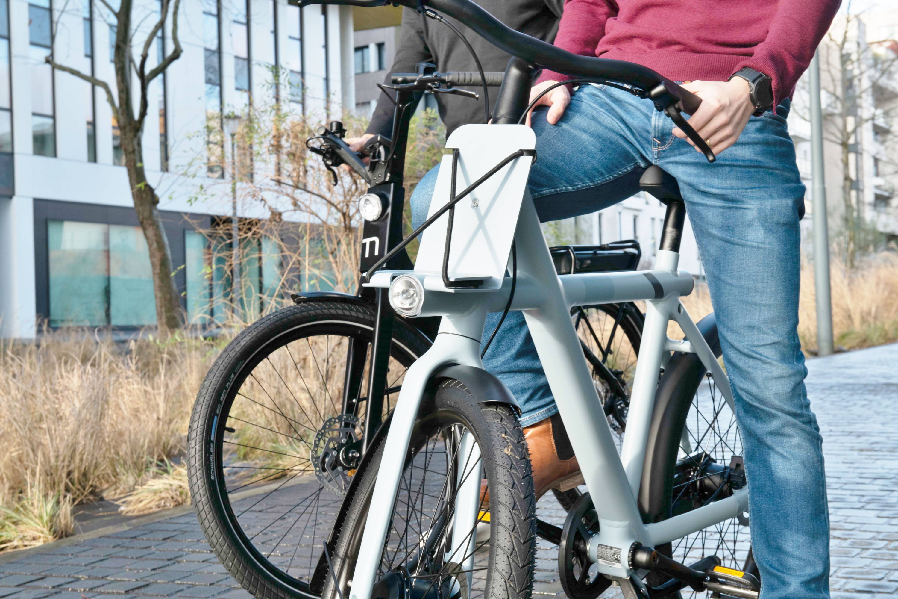 Close-up on the frame of two electric bikes ridden by two men.