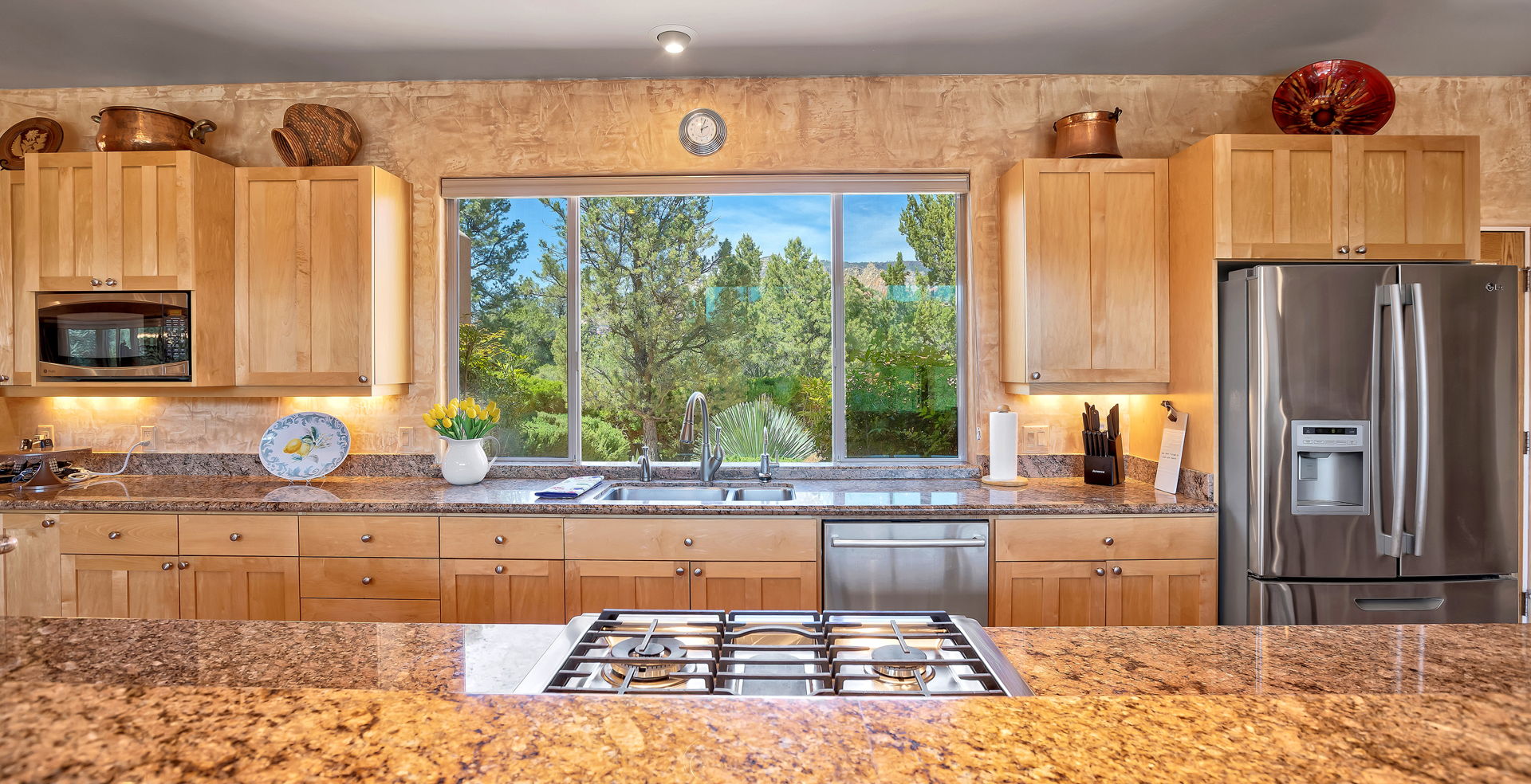 kitchen with a healthy amount of sunlight, refrigerator, dishwasher, gas stovetop, stainless steel microwave, and dark granite-like countertops
