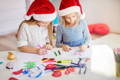 Two girls wearing Santa's hats drawing.