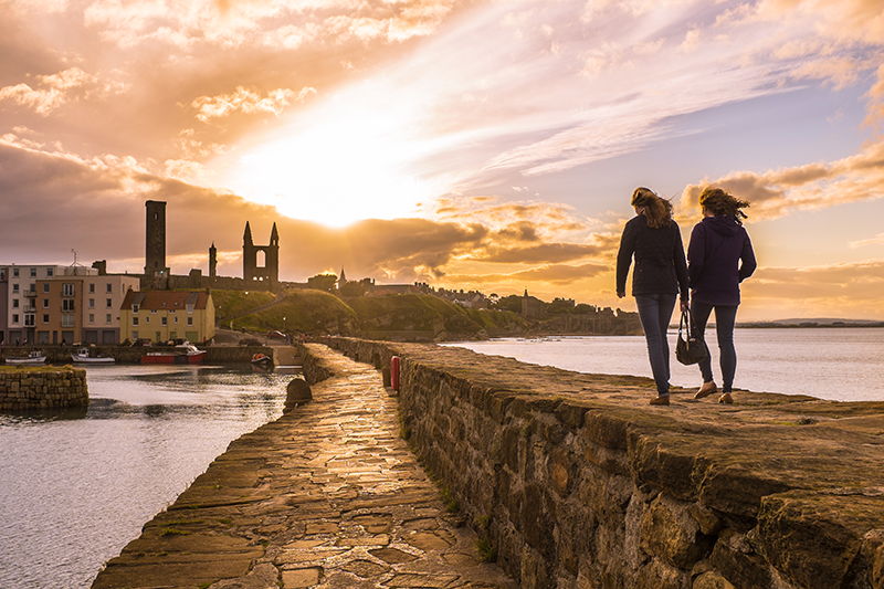Students on the pier at St Andrews with sunset in the background 