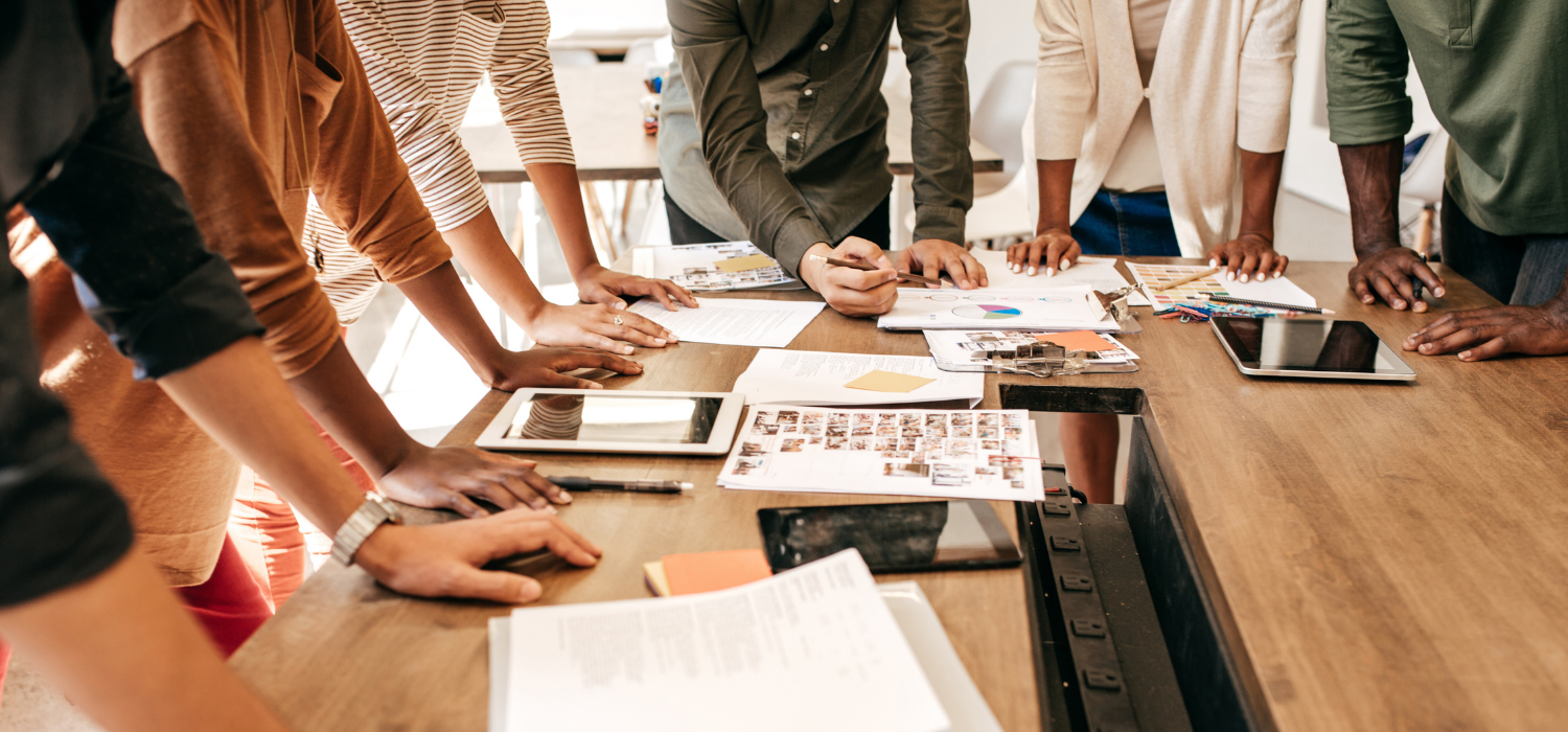 A team gathered around a desk looking at work