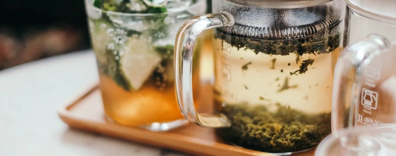Théière en verre thé jouvence de nekotea sur un plateau en bois, boisson détox pour une meilleure fonction hépatique.