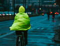 Cycliste en veste impermeable sur son velo en ville sous la pluie