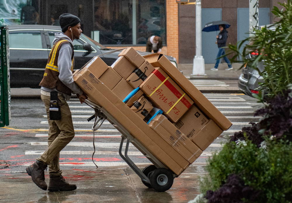 courier pushing a trolley of parcels in the street