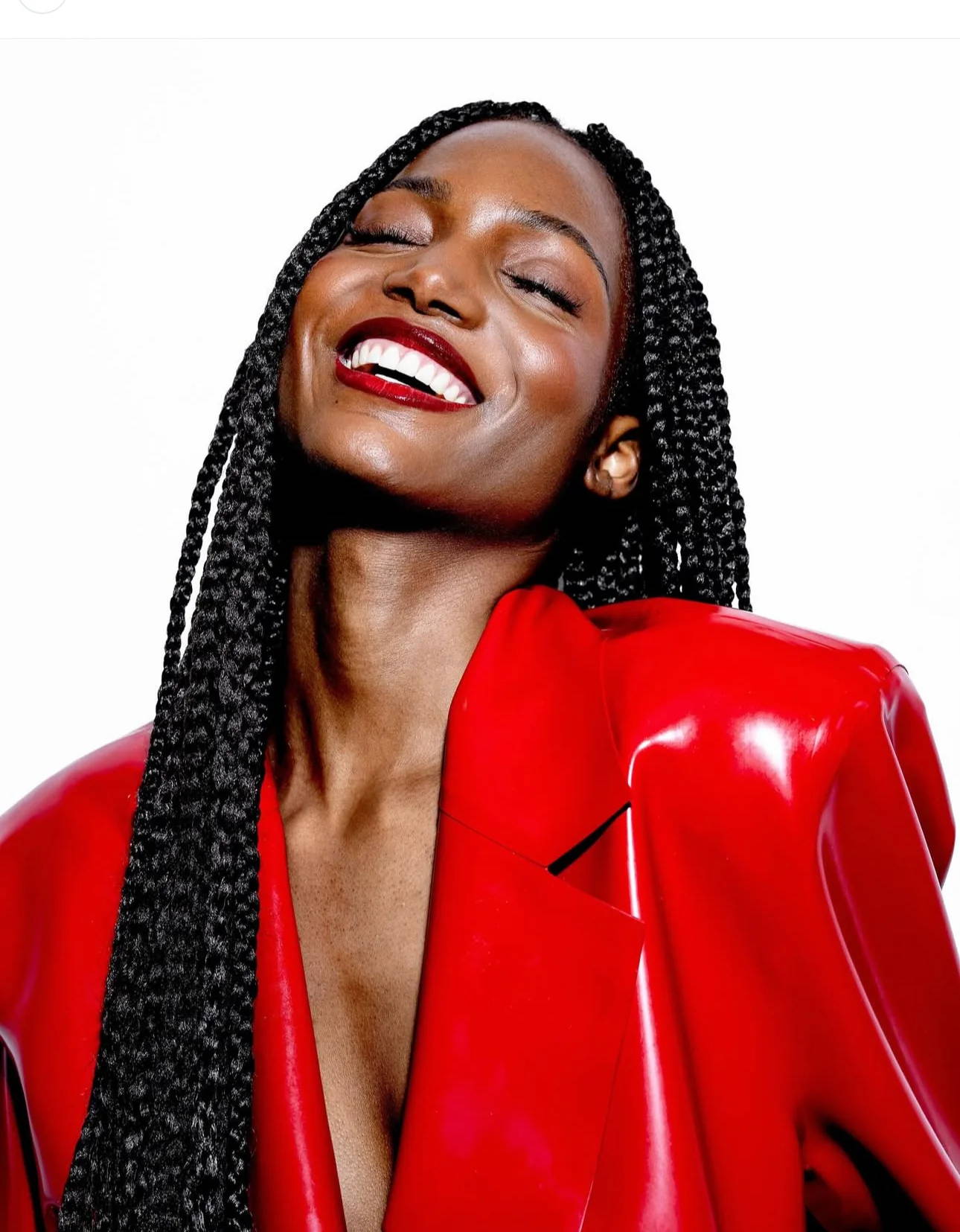 Model smiling in glossy red latex blazer by Vex Clothing, luxury latex fashion editorial look.