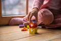 Close up on a little girl's hand stacking colorful wooden blocks.