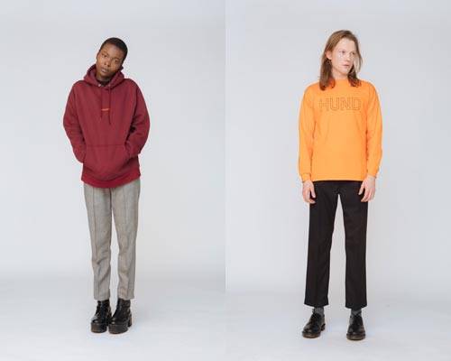 Woman wearing burgundy organic cotton hooded sweatshirt with grey cropped trousers and man wearing bright orange long sleeve tee with black cropped trousers from sustainable fashion brand Hund Hund