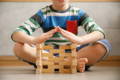 Boy posing next to his creation made out of wooden blocks. 