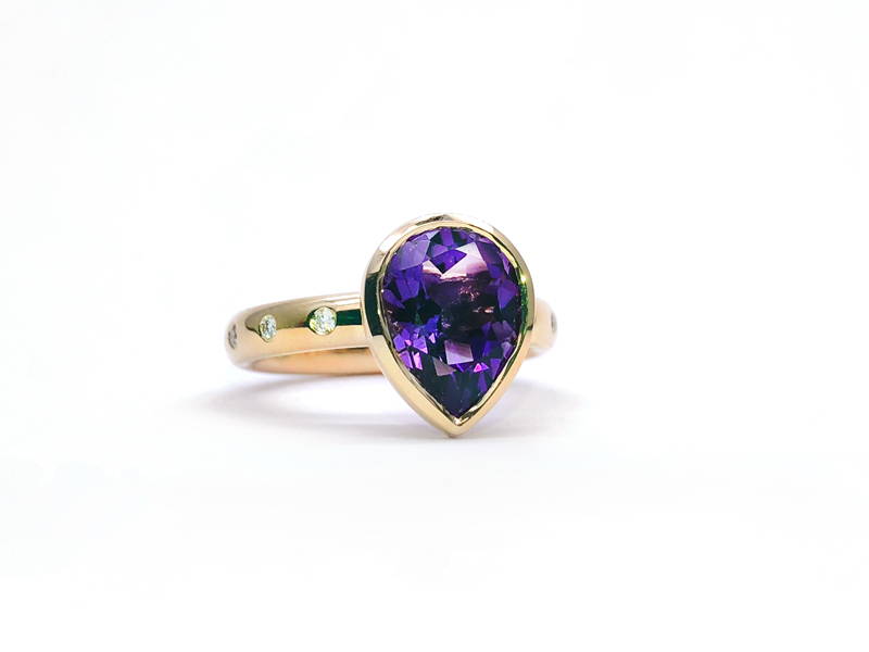 Yellow gold ring with diamond on the body and large pear cut amethyst in the center.