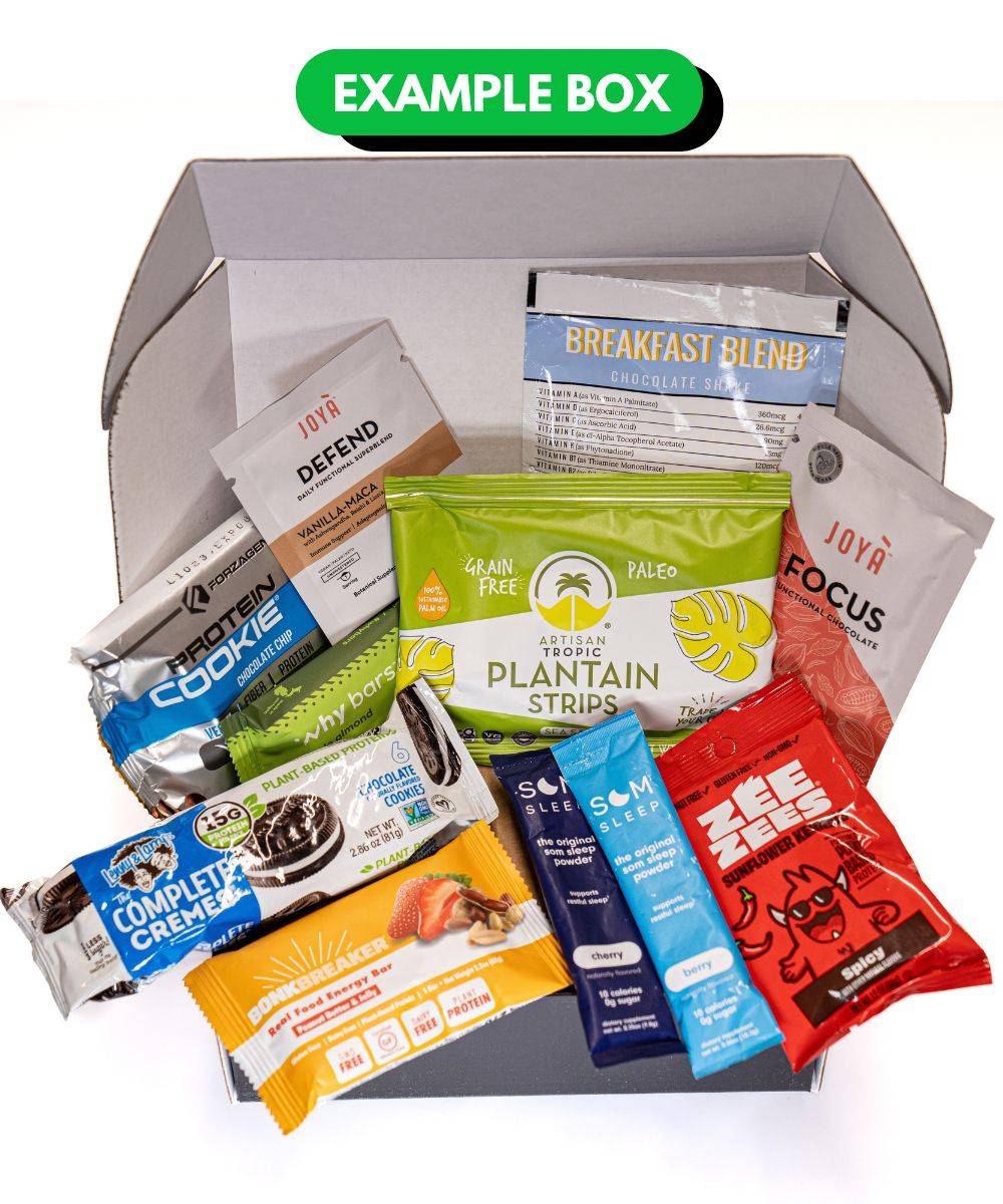 Snack box featuring several snacks and supplements for fitness enthusiasts such as Joya defend drink powder, Zee Zees spicy sunflower seeds, Artisan Tropic plantain strips, and more.