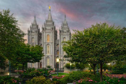 Salt Lake Temple surrounded by flourishing  trees and flowerbeds.