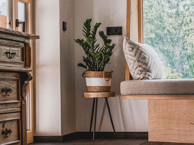 Sitzbank mit Kissen neben Fenster mit Aussicht in die Natur in einem Apartment von Hugo & Pepi in Mittelberg im Kleinwalsertal.
