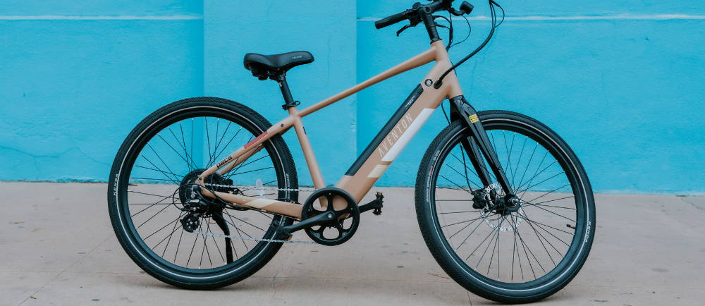 An aventon pace electric city bike in front of a blue wall