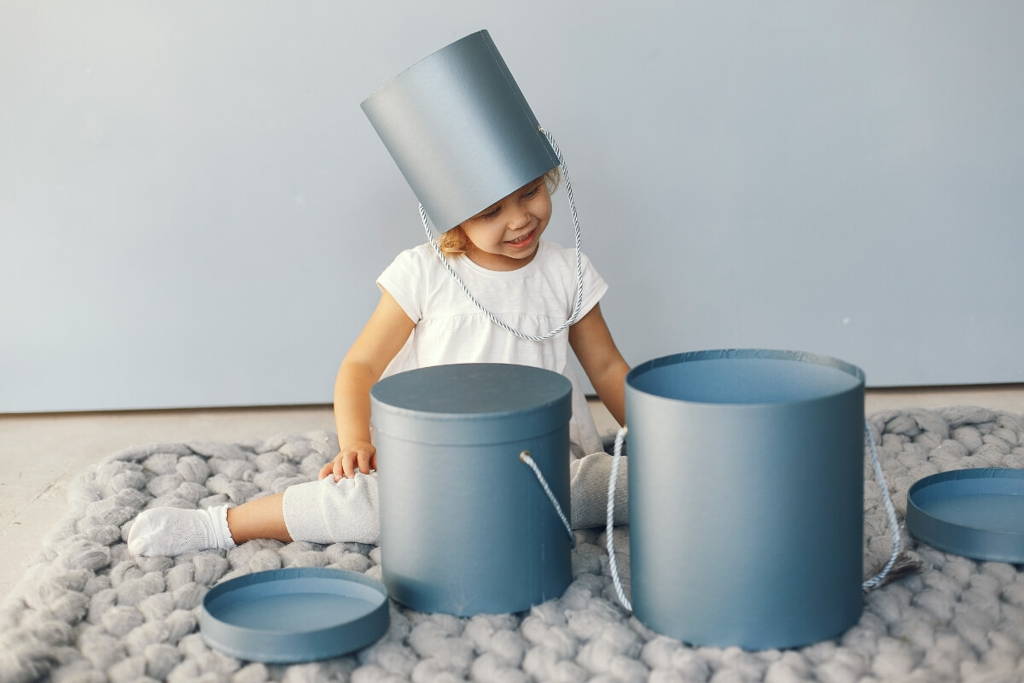 Little blonde girl playing with blue bins.