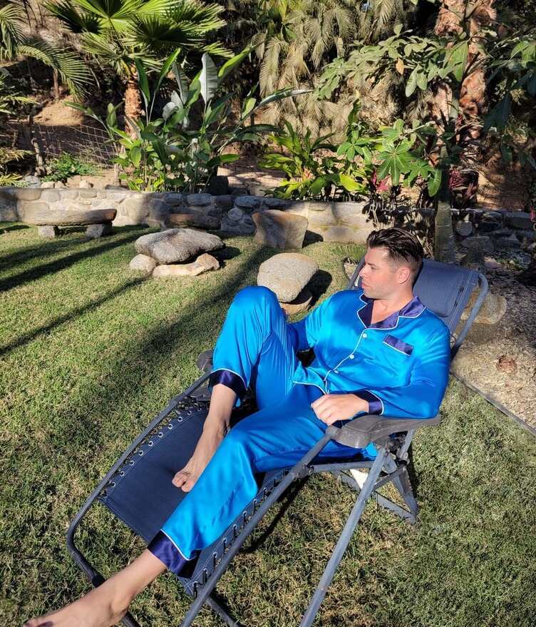 man wearing a blue silk pajama set while walking in the garden