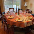 orange oval panama fabric tablecloth on a table with 9 chairs and little pumpkins on the plates
