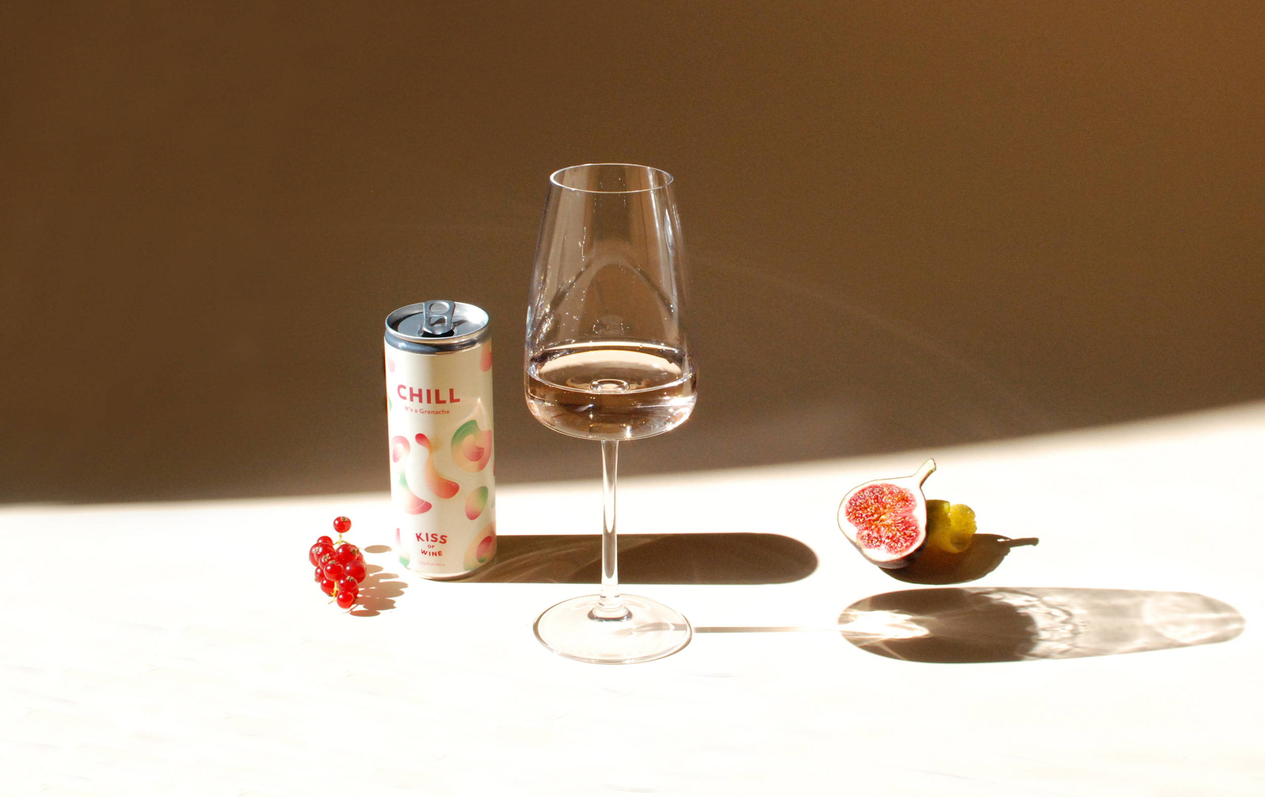 Poured glass of Chill Caladoc Rose surrounded by can, red berries and half a fig. 