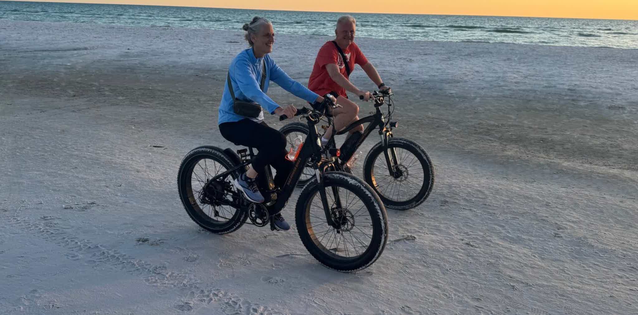 Imagen de recurso de una pareja recorriendo una playa con una e-bike.