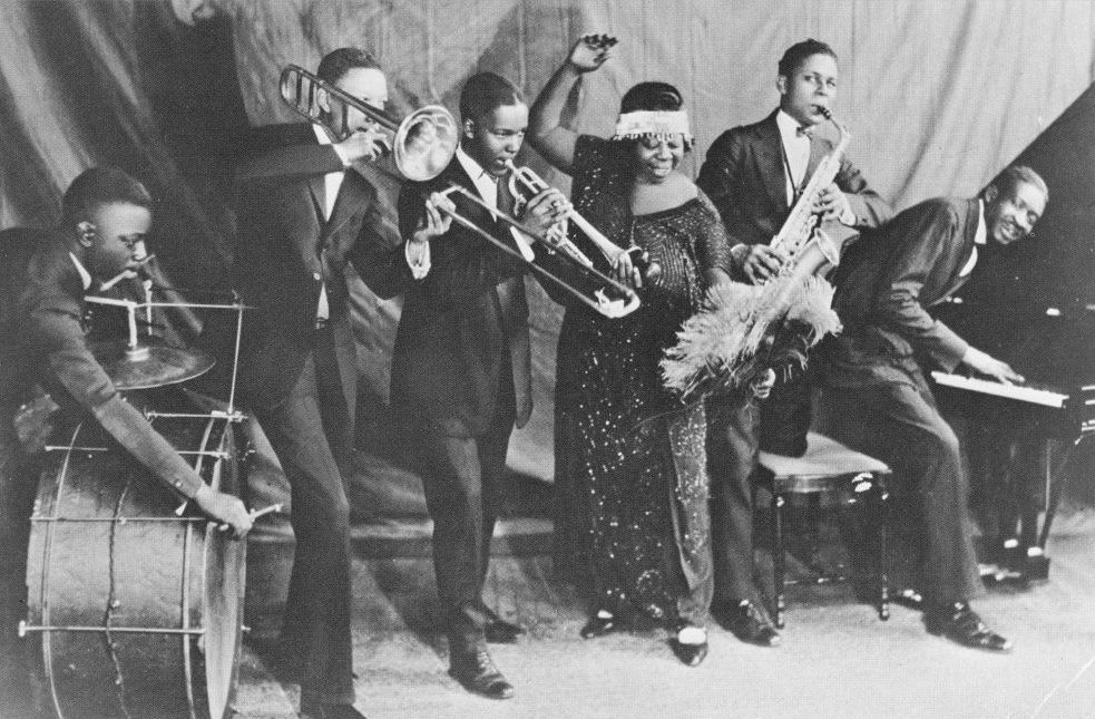Black and white image of Ma Rainey performing alongisde her jazz band.