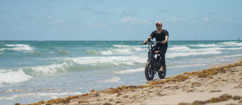 a man riding an electric moto style electric bike on the beach