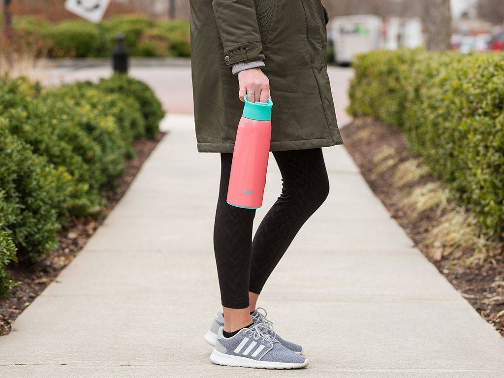 A woman carries a pink Swig water bottle
