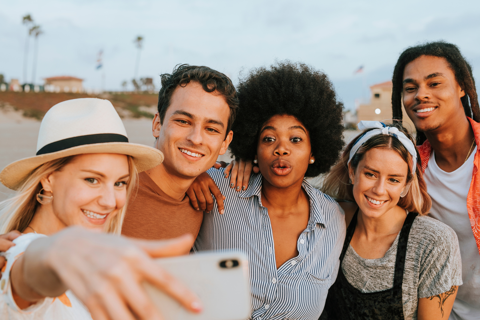 Image of a large group of attractive young and stylish multi ethnic friends taking a selfie together near a sunny outdoors environment.