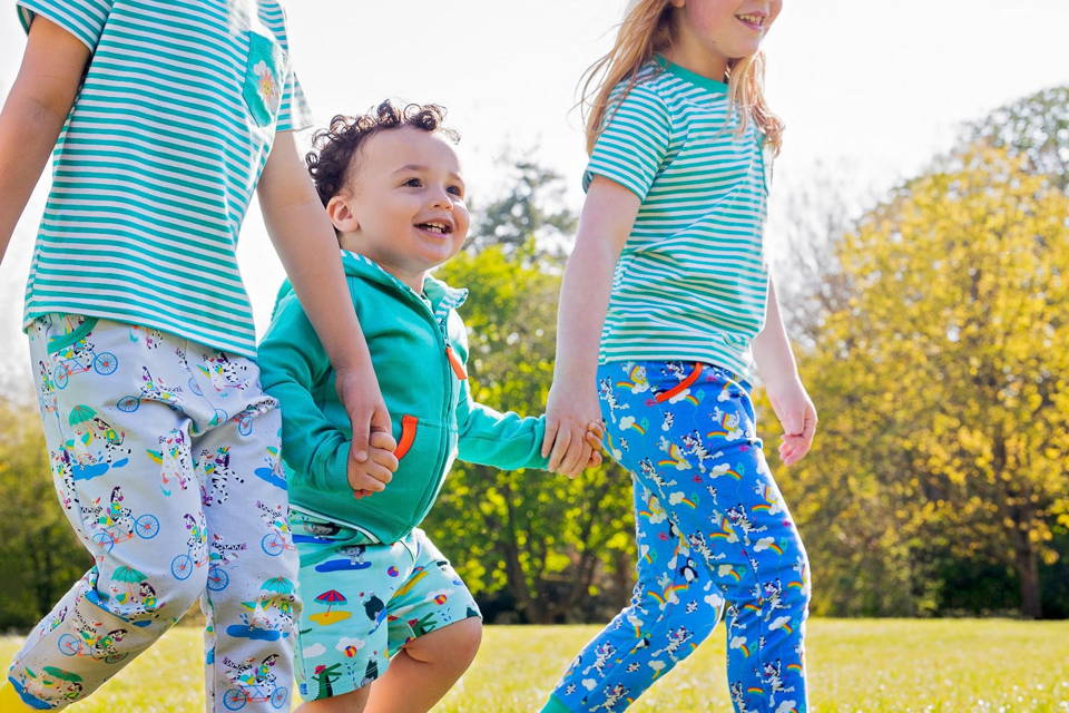 Image of three happy children holding hands, wearing Ducky Zebra clothes