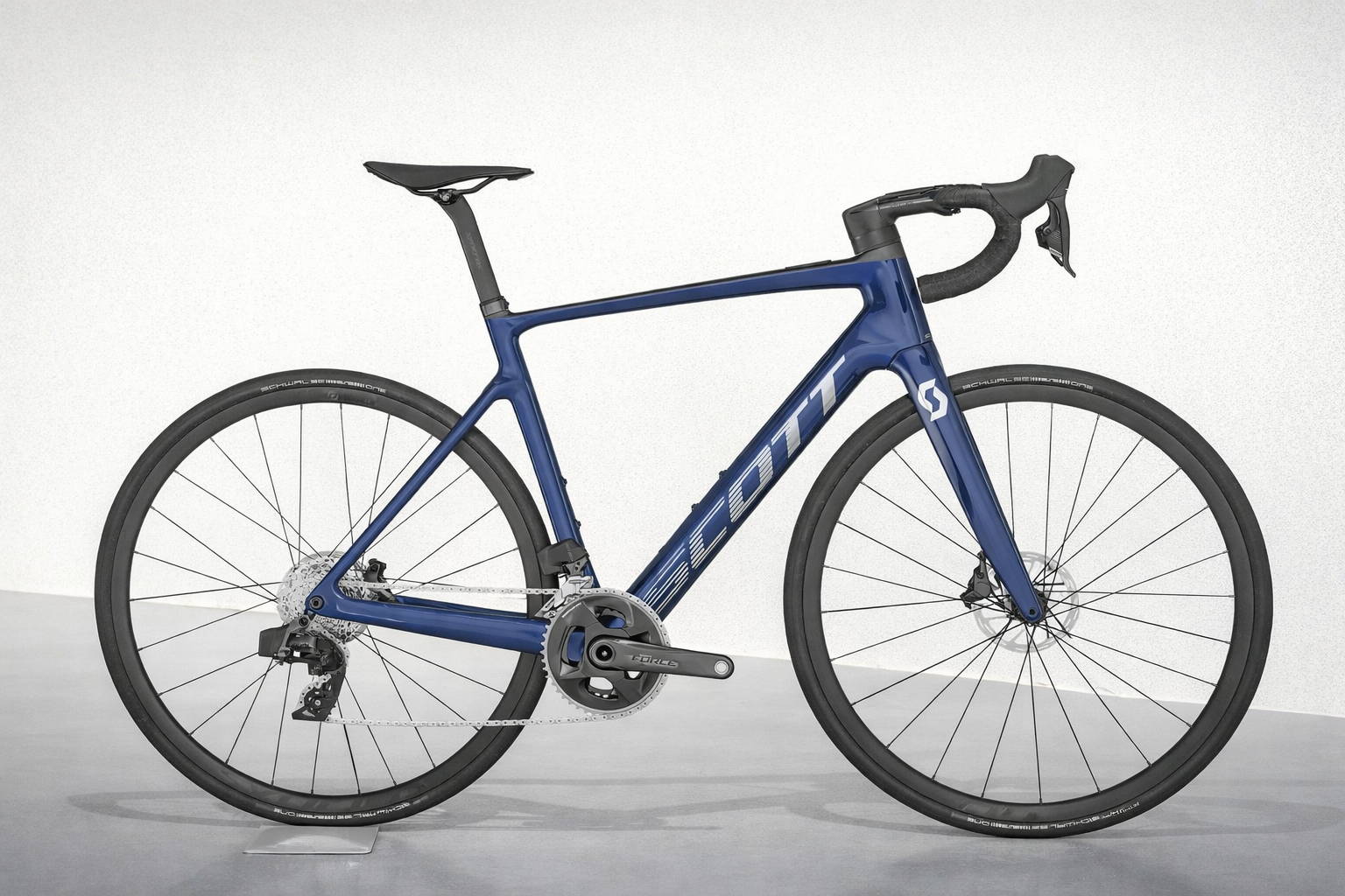 Scott Addict carbon racefiets met SRAM Force groepset en Schwalbe banden, blauwe racefiets met schijfremmen in zijaanzicht op neutrale achtergrond.