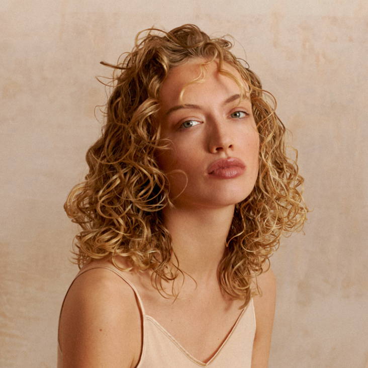 Davines model with blonde short curly hair with bangs