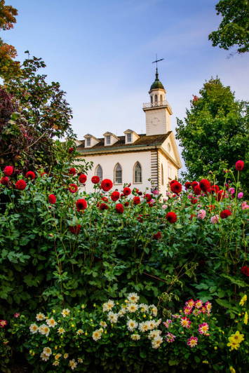 Kirtland Temple standing behind a wall of flowers.