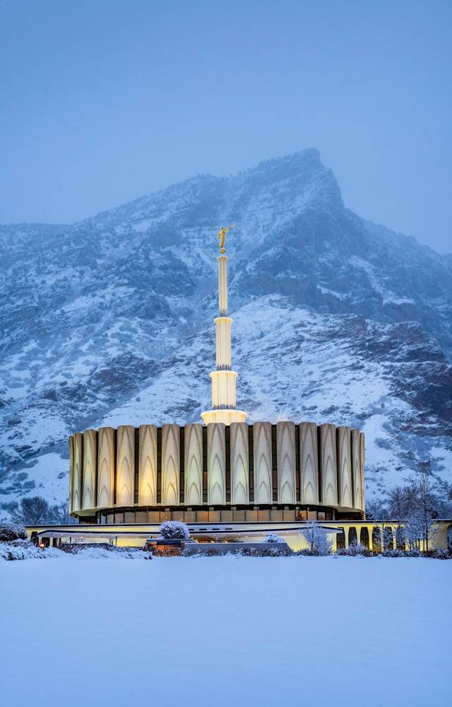 Vertical photo of the Provoe Temple glowing with snowy mountains in the backdrop. 