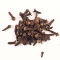 A pile of dried whole cloves scattered on a white background.