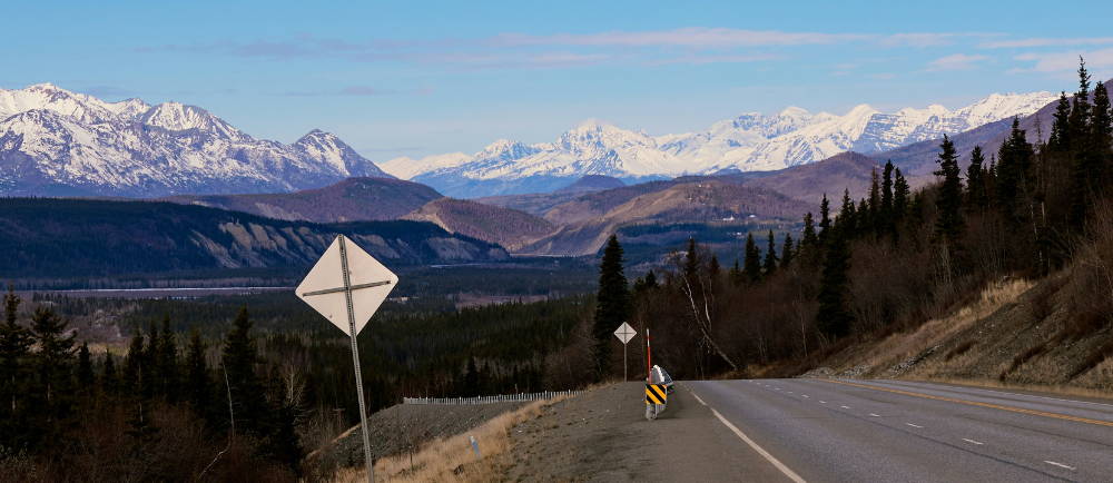 a quiet highway below the mountains in Alaska