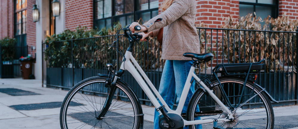 a woman walking next to her Gazelle Medeo elctric bike in the city