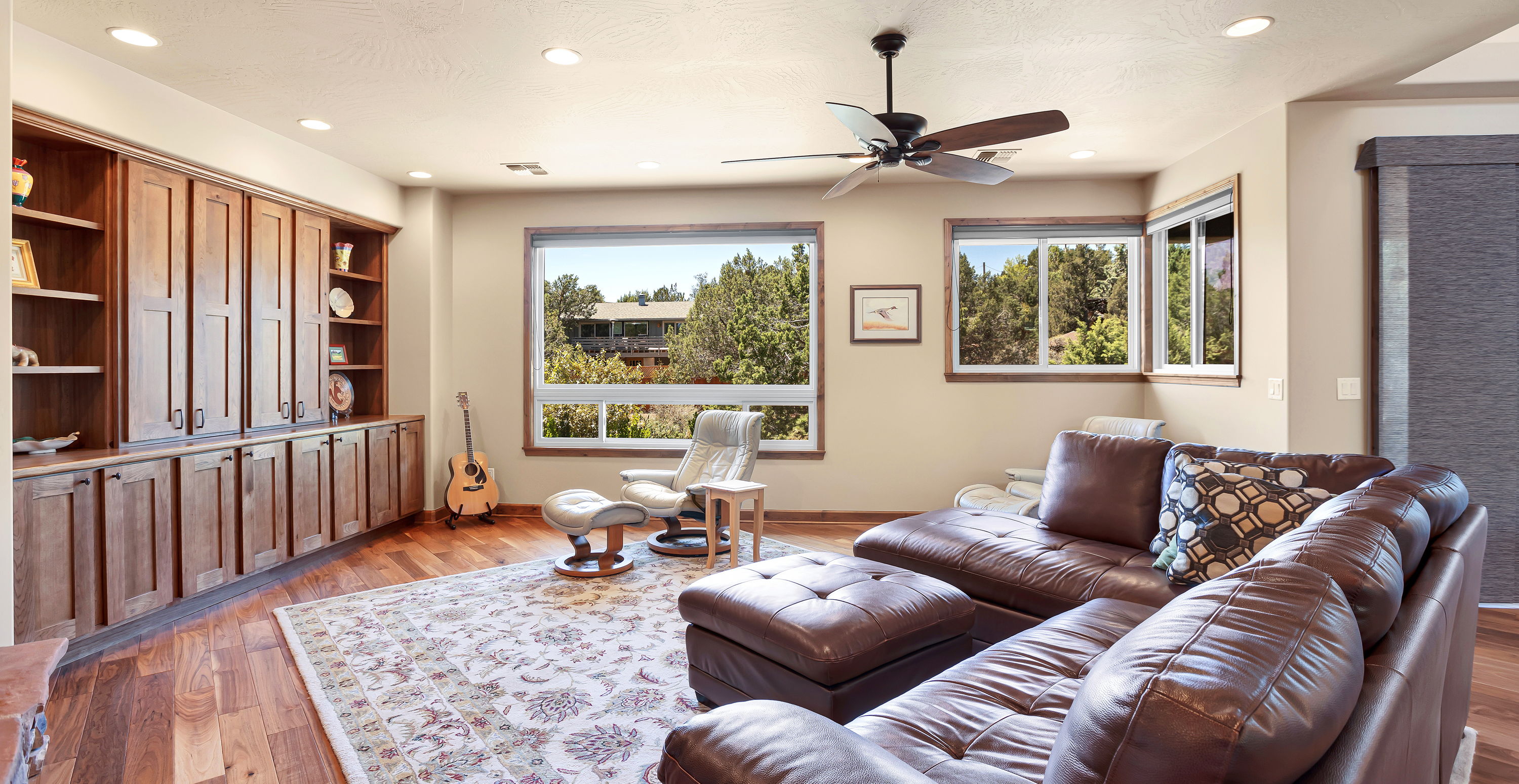 hardwood floored living room featuring a ceiling fan and natural light