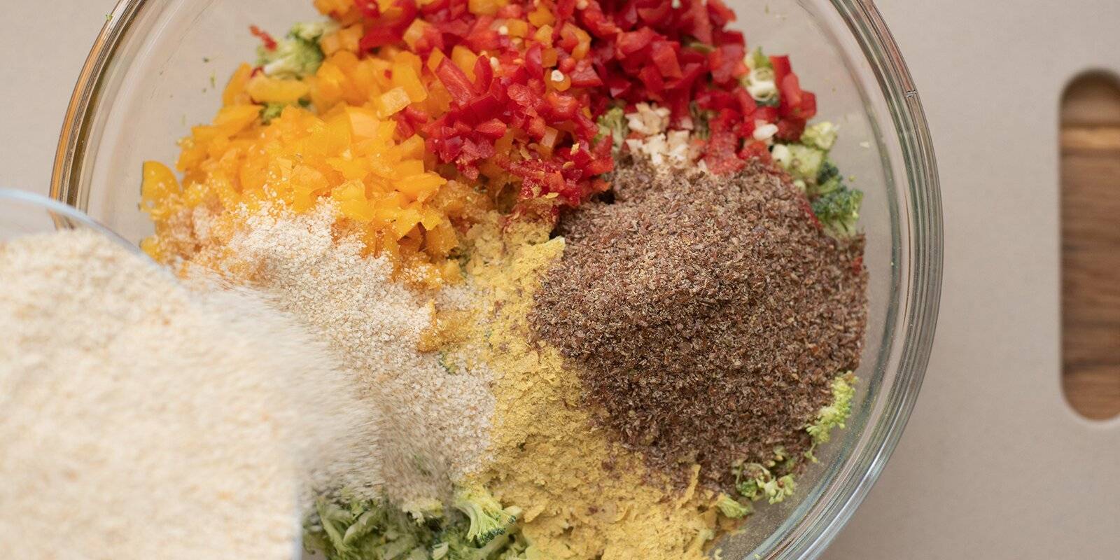 Pouring Veggie Nugget ingredients into a glass bowl.