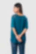 A woman in a teal short-sleeve top with lace shoulders, shown from the back with her hands behind her, wearing blue jeans against a white background.