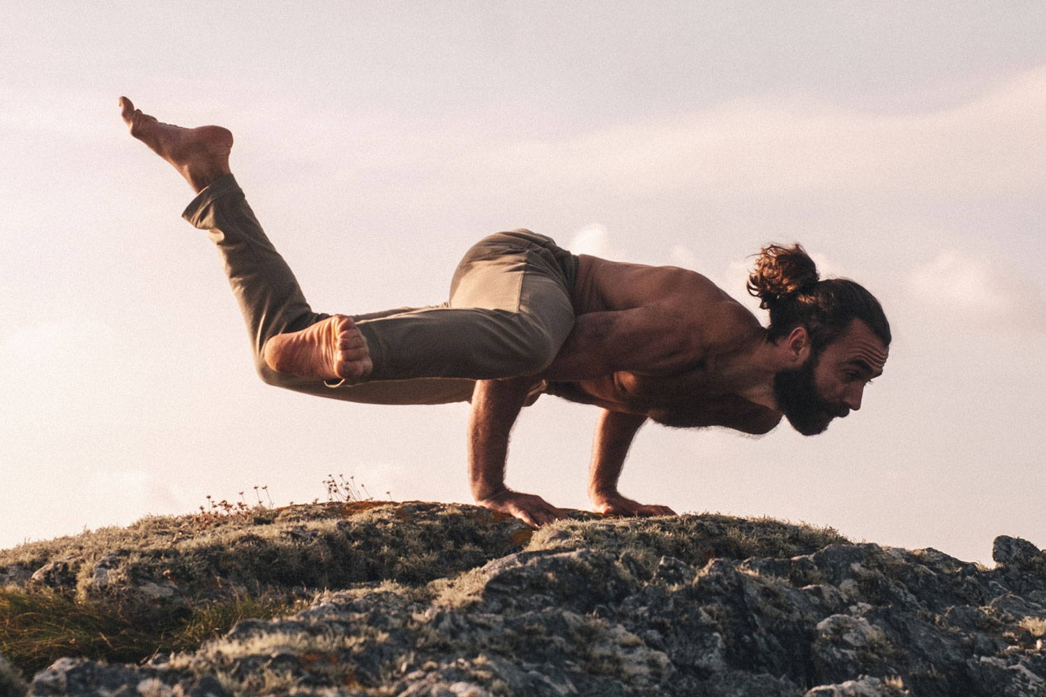 Leo Oppenheim balancing on a rock wearing So We Flow... Solace Yoga Pants in Sage
