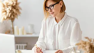 Vue de face d'une belle femme au travail avec un stylo et un ordinateur portable.