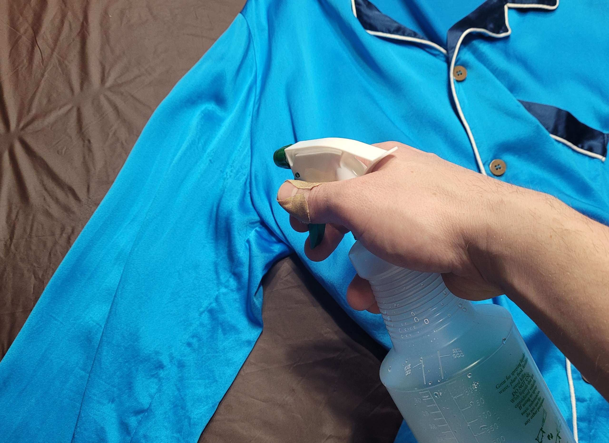 photo of a person spraying a cleaning solution onto sweat stains of silk pajamas