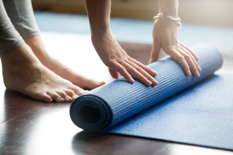 Eine Frau bereitet sich aktiv auf ihre Yoga Stunde vor.