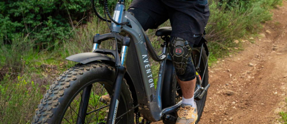 a person riding a green Aventon Aventure fat tire electric mountain bike