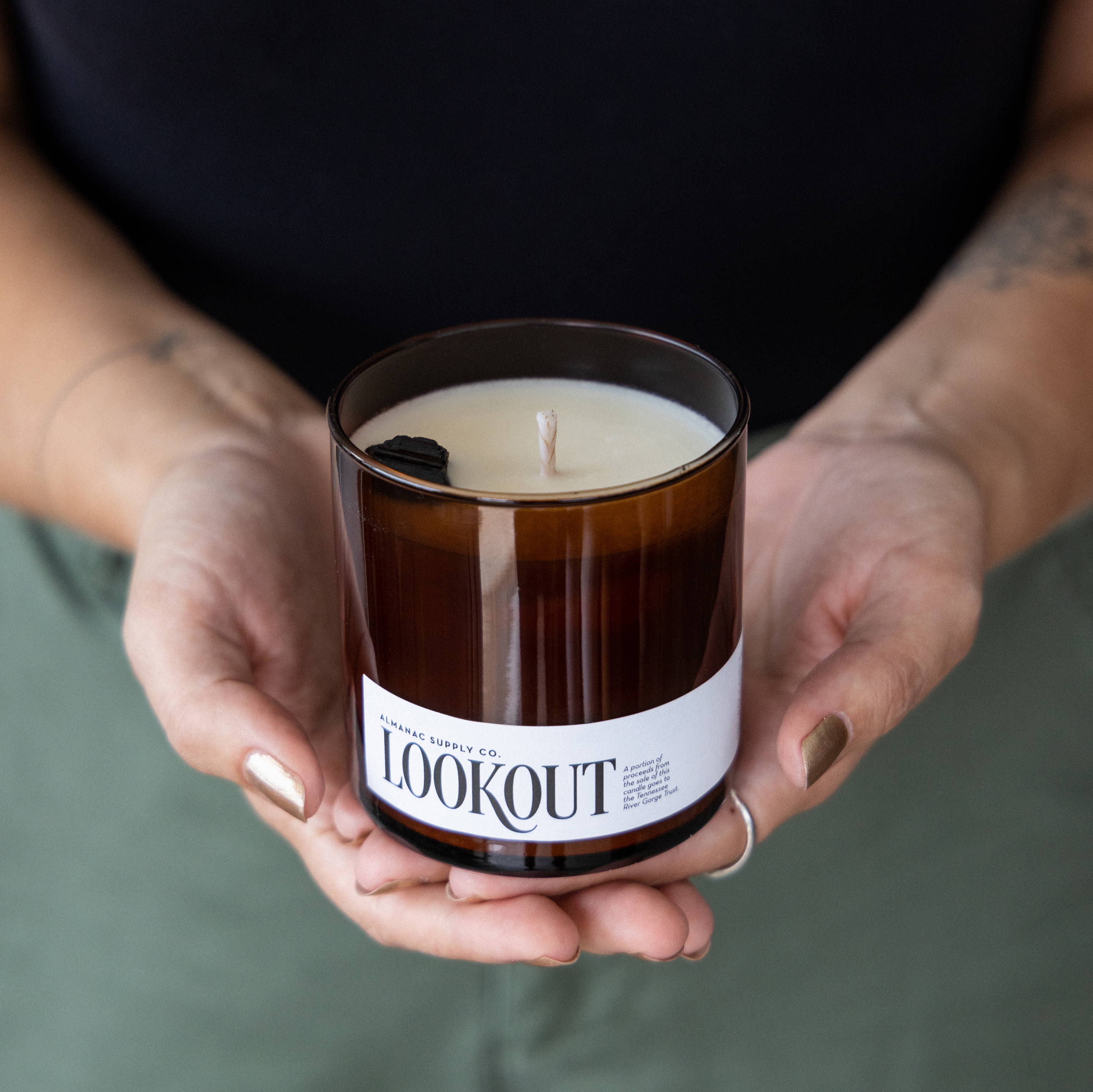 Hands holding a Lookout Candle in amber jar, named after the Chattanooga mountain