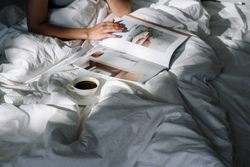 Person reading a magazine in bed with a cup of coffee beside herPhoto by cottonbro from Pexels