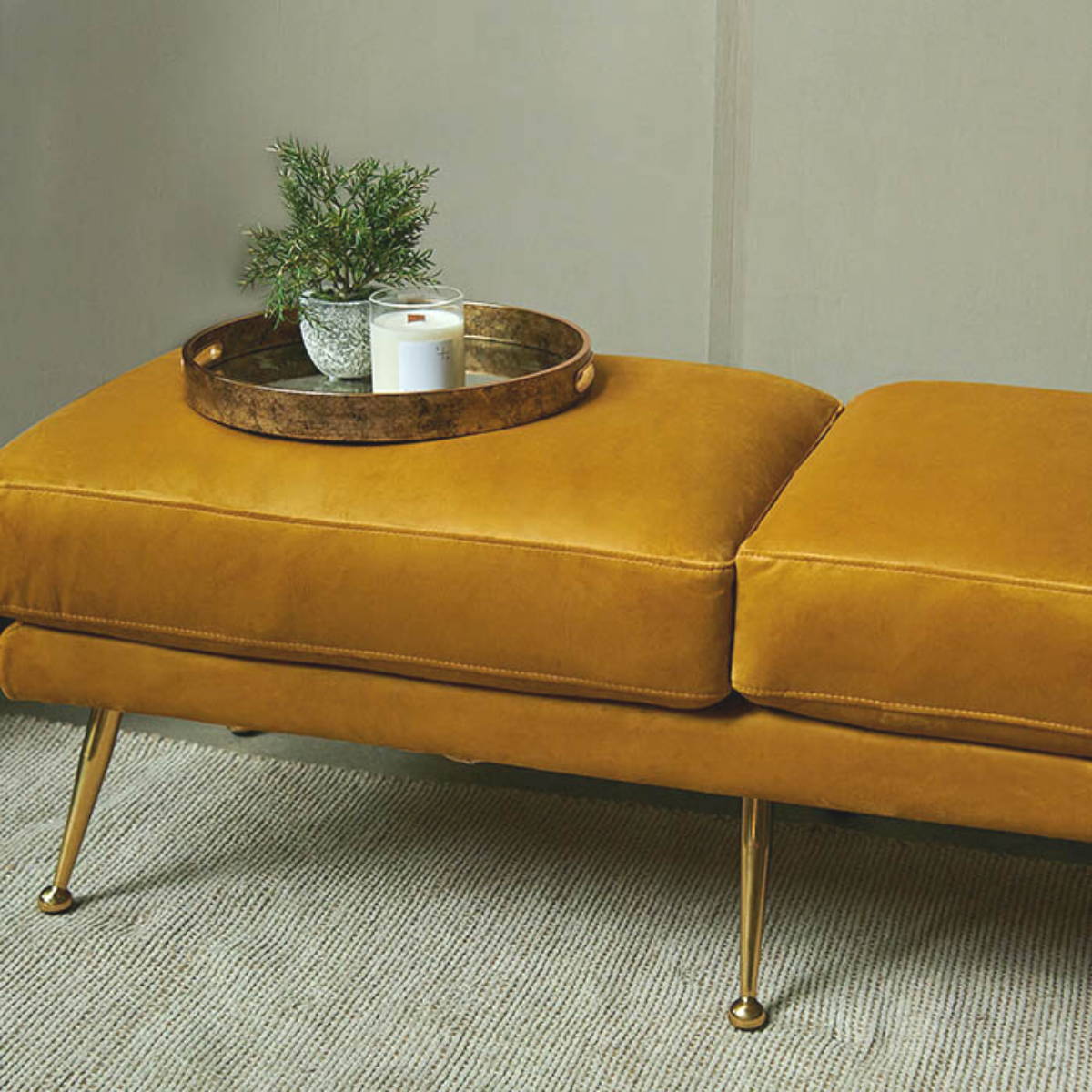 a mustard gold velvet bench seat with metal legs